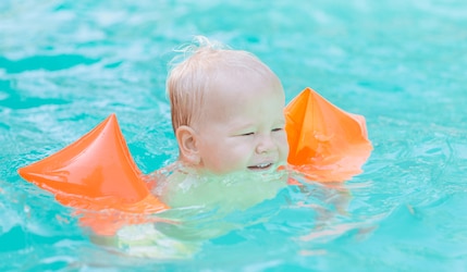 Baby im Pool mit Schwimmflügel