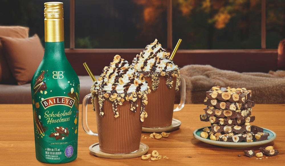 Baileys Schokolade Haselnuss Flasche, daneben zwei Tassen mit Sahne.png