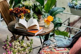 Sommer-Balkon mit vielen Pflanzen, Buch und Getränk auf einem Tisch