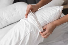 Person wechselt Bettwäsche