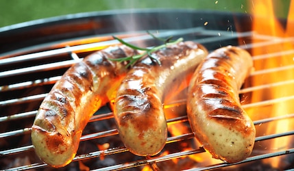 Bratwurst auf einem Grill mit Feuer