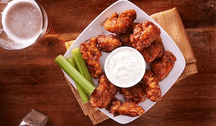Buffalo Hot Wings auf einem Teller mit Dip, Bier und Sellerie