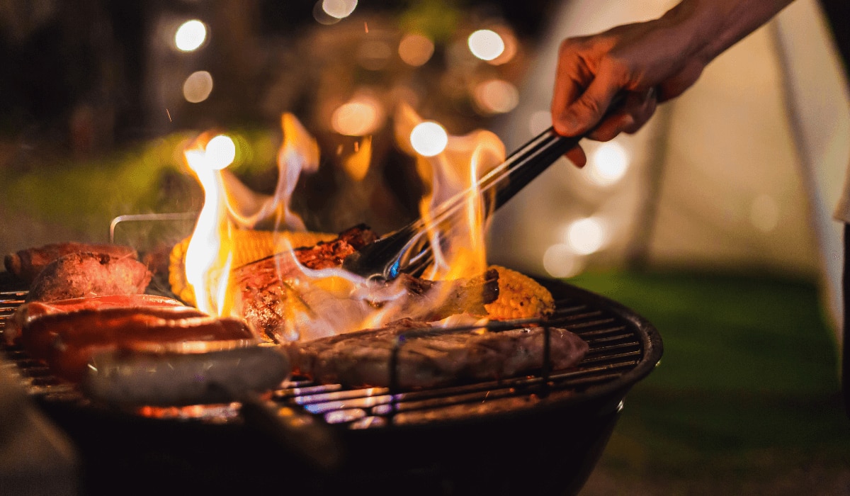 Camping-Grill bei Nacht mit verschiedenen Lebensmitteln
