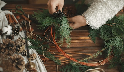 Frau, die Adventskranz selber bastelt mit Tannenzweigen