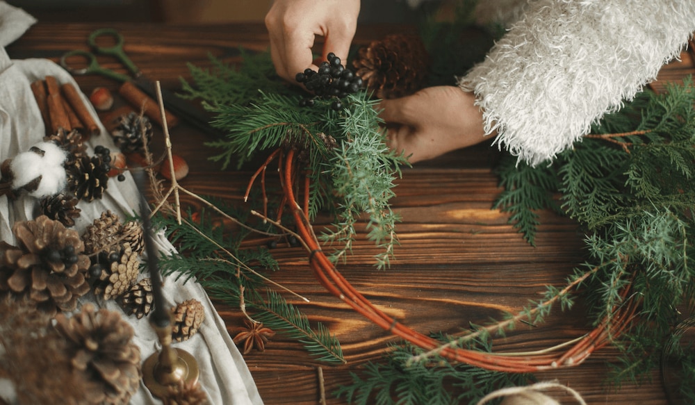 Frau, die Adventskranz selber bastelt mit Tannenzweigen