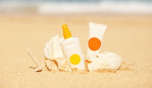 Eine Flasche, Tube und Muschel im Sand