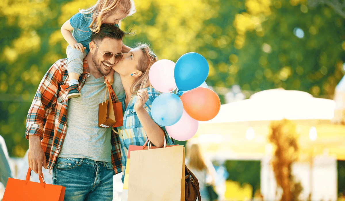 Familie mit Kind geht shoppen mit Luftballons