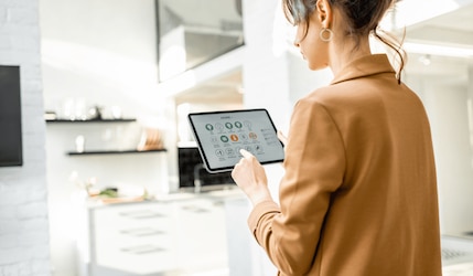 Frau bedient ein Smart Home mit einem Tablet in ihrer Wohnung