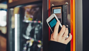 Frau bezahlt per Handy an einem Lebensmittelautomat