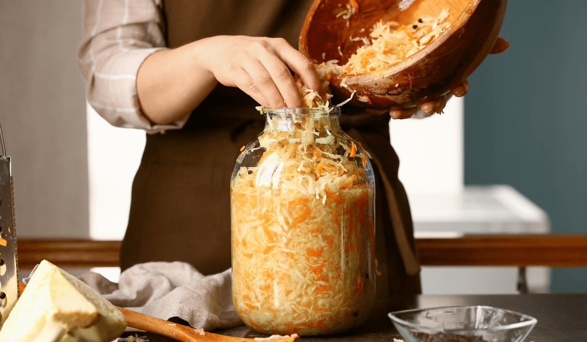 Frau fermentiert frisches Sauerkraut in einem großen Einmachglas