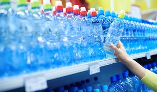 Frau greift nach einer Wasserflasche im Supermarkt