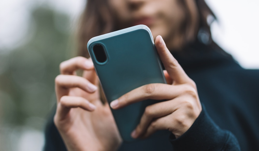 Frau hält Smartphone in blauer Handyhülle