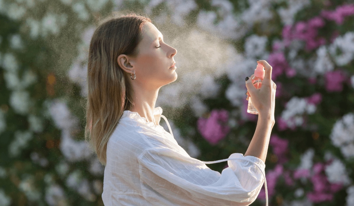 Frau sprüht sich Wassernebel ins Gesicht