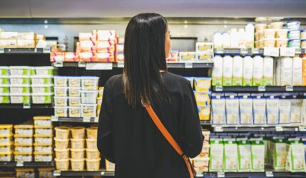 Frau steht in einem Supermarkt vor einem Kühlregal mit Butter