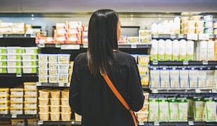 Frau steht in einem Supermarkt vor einem Kühlregal mit Butter