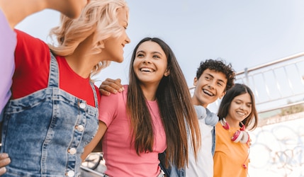 Gruppe glücklicher Jugendlicher gehen Arm in Arm