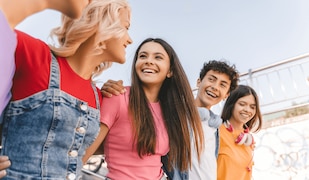 Gruppe glücklicher Jugendlicher gehen Arm in Arm