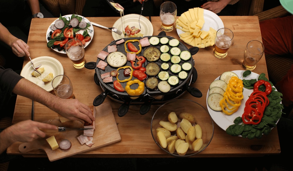 Gruppe von Menschen um einen Raclette-Grill