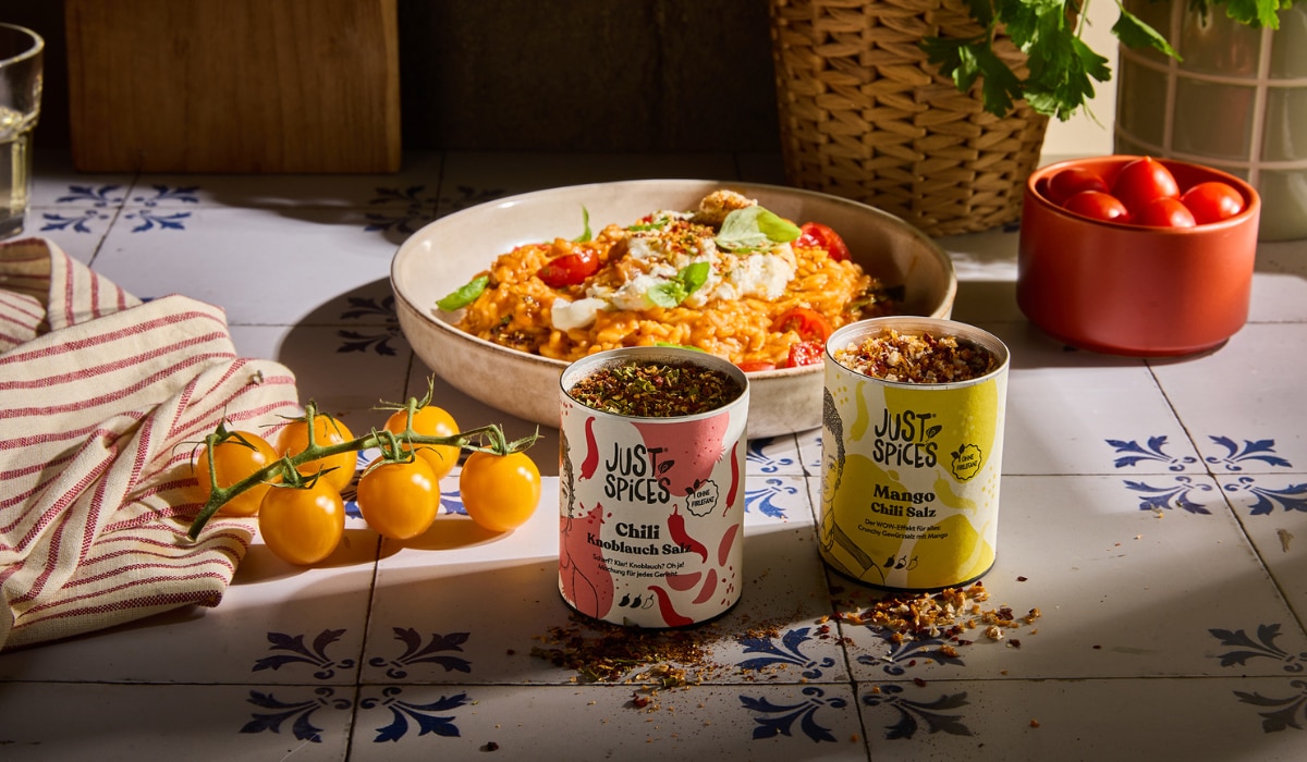 Just Spices zwei Gewürze, im Hintergrund Teller mit Reis, daneben Tomaten