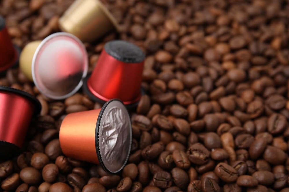 Bunte Kaffeekapseln liegend auf Kaffeebohnen