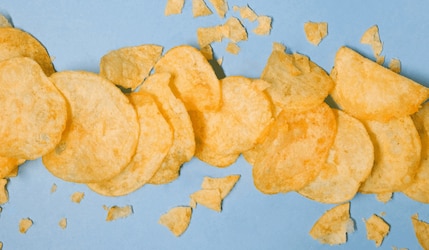 Kartoffelchips aufgereiht vor blauem Hintergrund