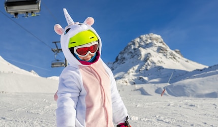 Kind in einem Kigurumi Ski-Skostüm beim Ski im Schnee