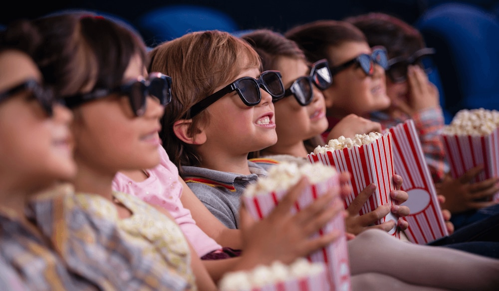 Kinder essen Popcorn und gucken einen Film im Kino