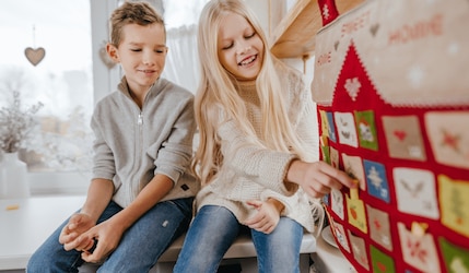 Kinder öffnen zu Weihnachten einen Adventskalender