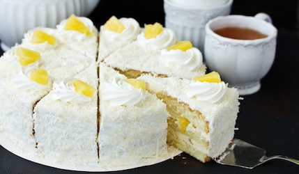 Kokos Ananas Torte mit Tasse Tee im Hintergrund.png