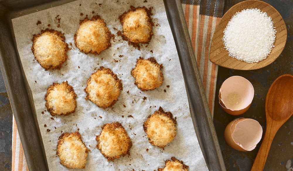 Frisch gebackene Kokosmakronen auf einem mit Backpapier belegtem Blech