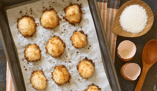 Frisch gebackene Kokosmakronen auf einem mit Backpapier belegtem Blech