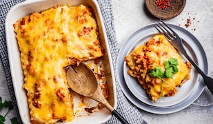 Lasagne in einer Auflaufform und als Stück auf einem Teller