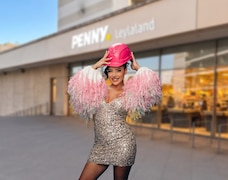 Leyla Heiter steht vor dem Penny Leylaland in Frankfurt und trägt ein Glitzerkleid und einen pinkfarbenen Bauhelm.
