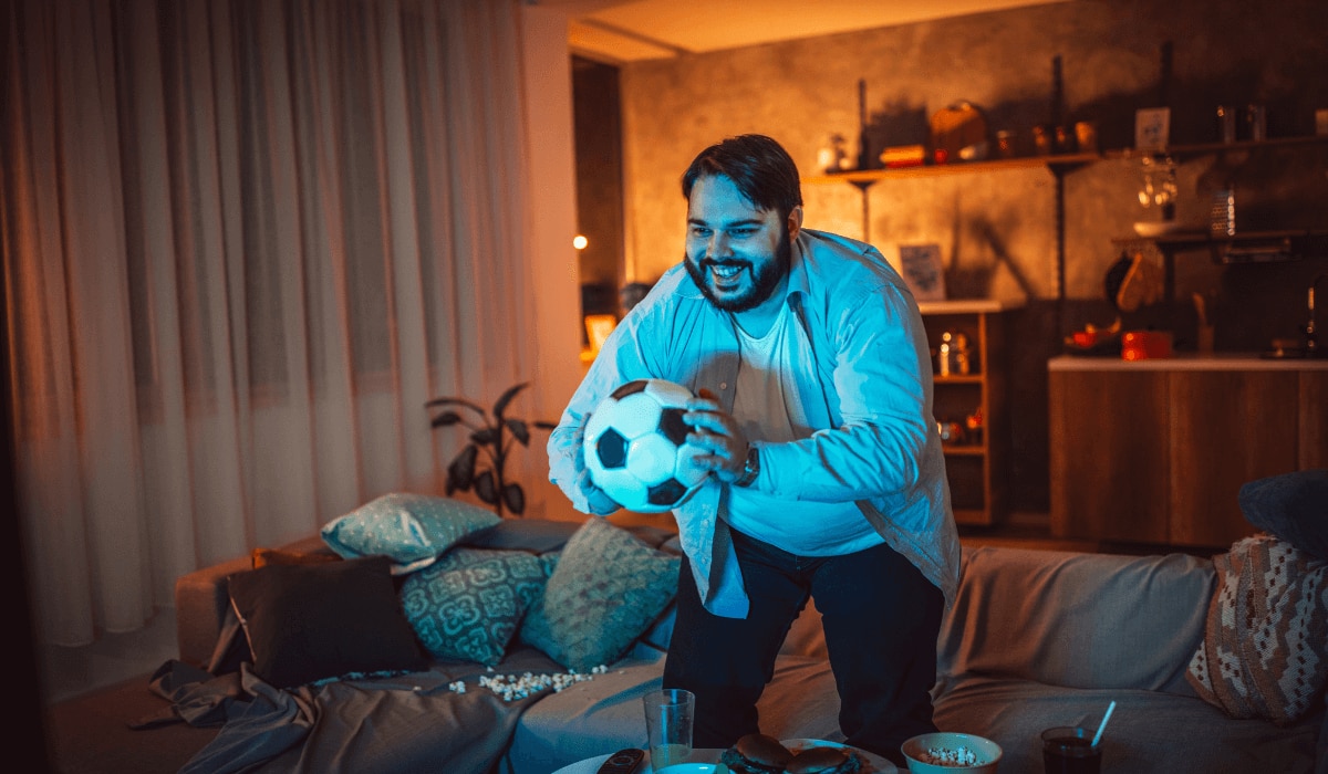 Mann guckt zu Hause Fußball auf einem Fernseher und freut sich