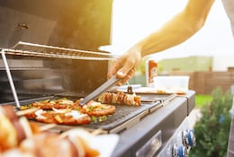 Mann steht an einem Grill und grillt