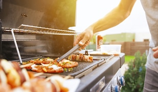Mann steht an einem Grill und grillt