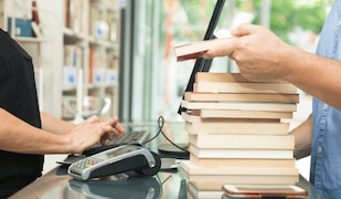 Mann verkauft gebrauchte Bücher in einem Geschäft an der Kasse