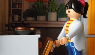 Playmobil Frau mit schwarzen Haaren öffnet Playmobil Herd in einer Playmobil Küche