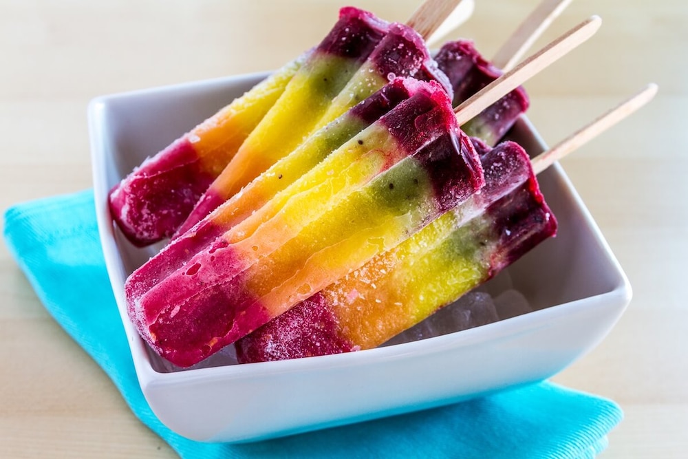 Regenbogen-Eis am Stiel in Schale liegend