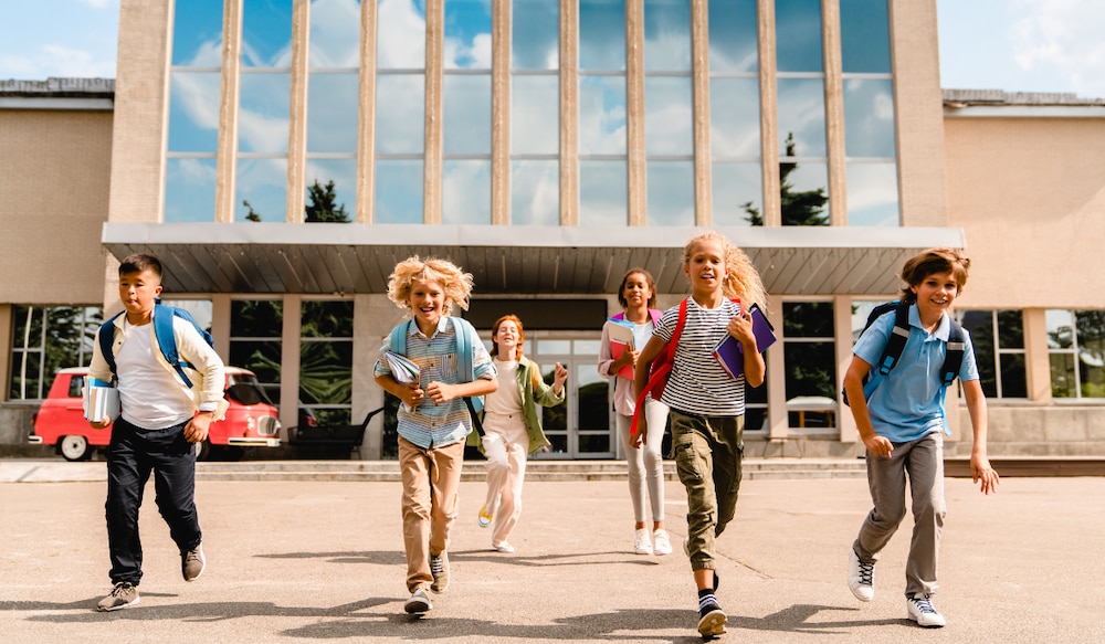 Schüler rennen fröhlich aus einer Schule