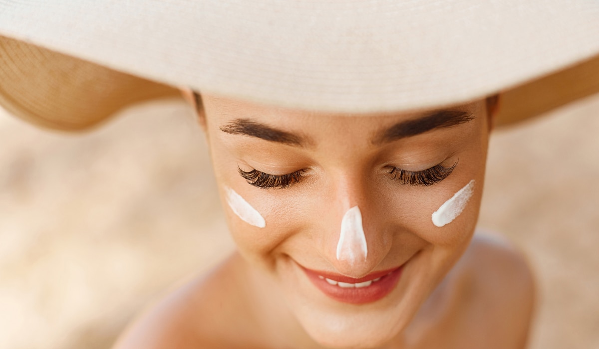 Frau mit Hut und zwei Streifen Sonnencreme