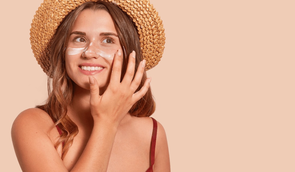 Frau mot Hut probiert Sonnencremes mit Anti-Aging Effekt 