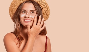 Frau mot Hut probiert Sonnencremes mit Anti-Aging Effekt 