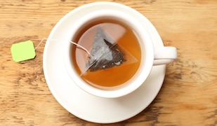 Teetasse mit Tee und einem Teebeutel auf einem Holztisch von oben fotografiert