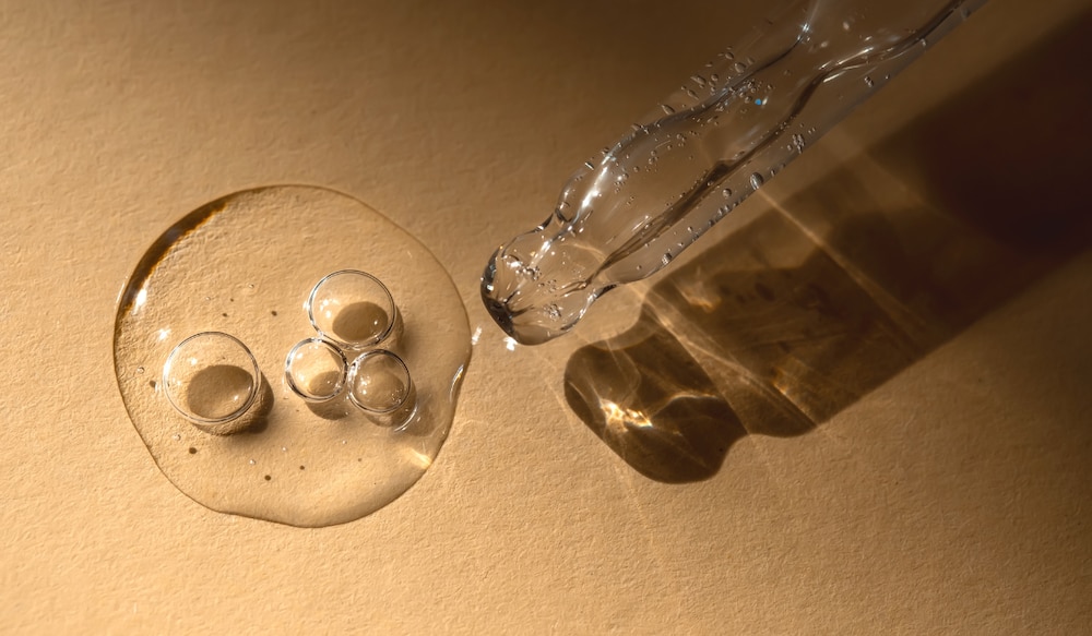 beiger Hintergrund, Pipette mit klarer Flüssigkeit