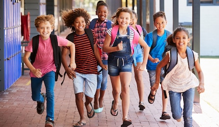 glückliche Schüler rennen aus einer Schule