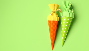 grüner Hintergrund, eine orange und grüne Schultüte.png