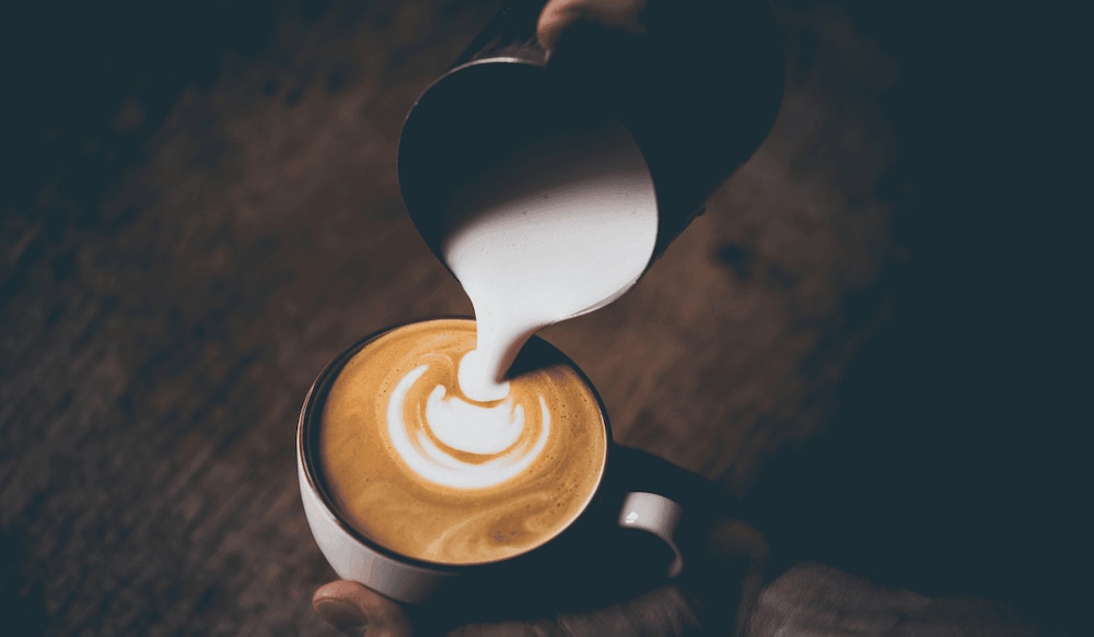 Barista Milch in den Kaffee gießen