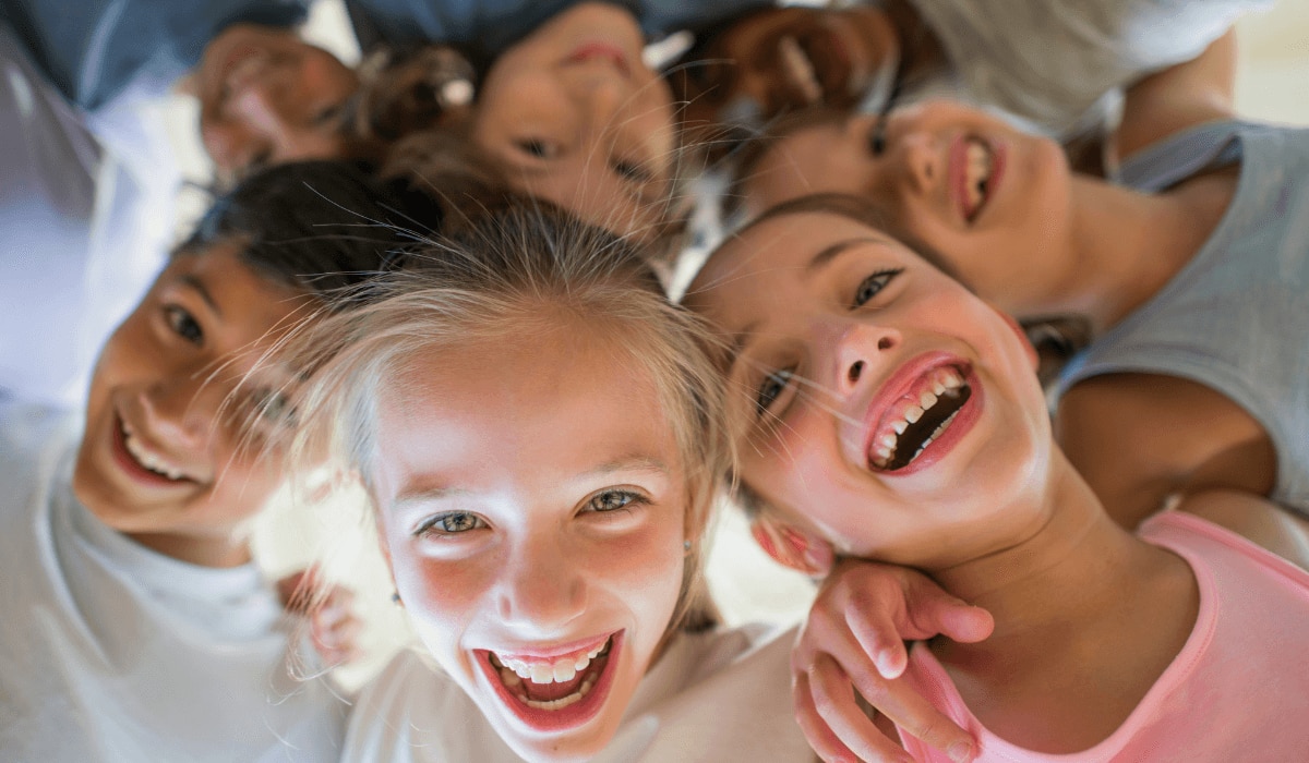 lachende Kinder gucken von oben in die Kamera