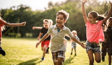 lachende Kinder rennen durch die Natur